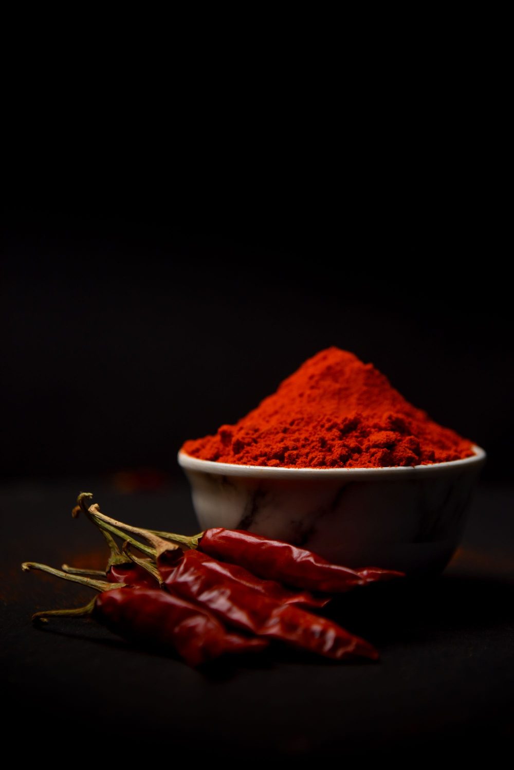 Red chilli powder in a bowl with whole dried chillies